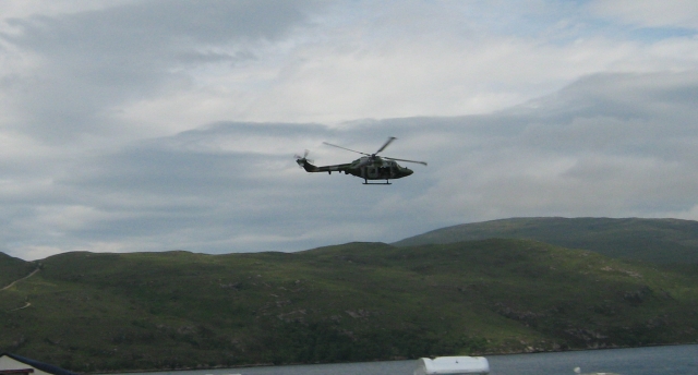 an army helicopter flying over loch broom with the campsite in the foreground
